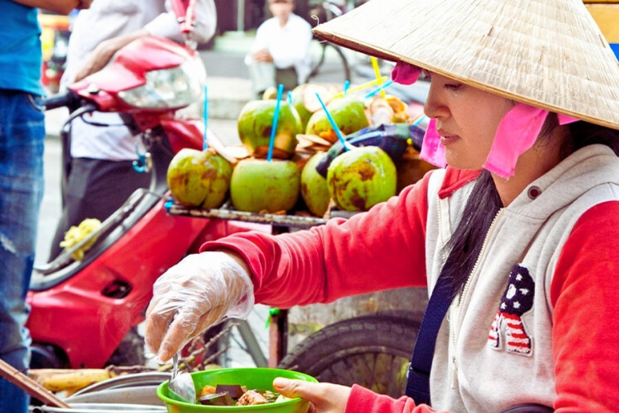 Vietnamese street food vendor selling coconut dessert at local market – Auasia Travel